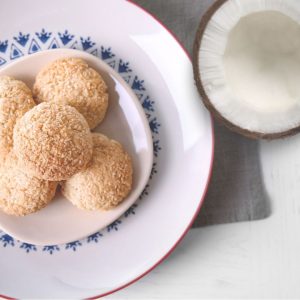 Zitronen-Kokos Kekse auf einem Teller, daneben eine halbe Kokosnuss zum Thema Sommerkekse