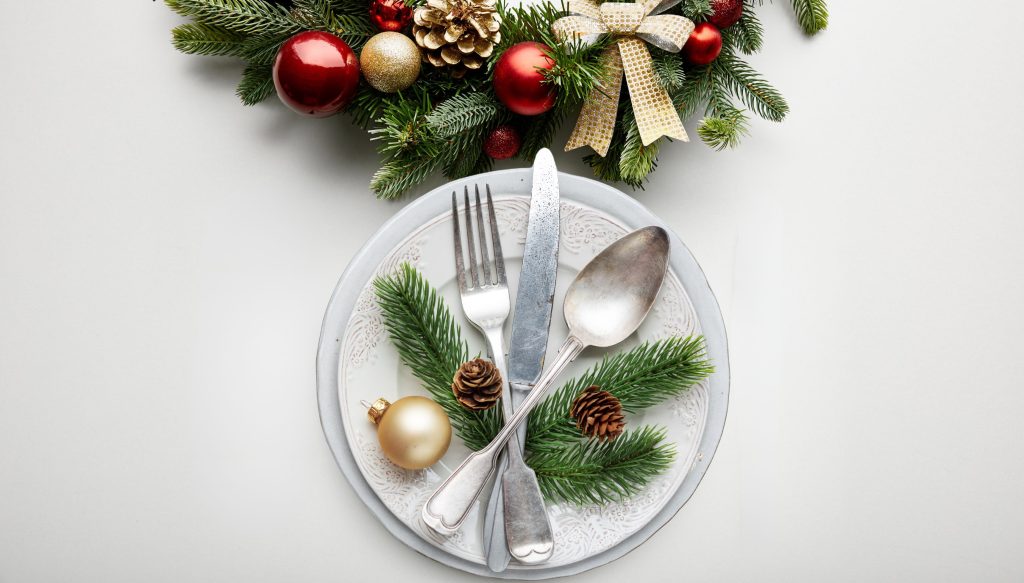 Weihnachtlich gedeckter Tisch mit Teller, Tannengrün und Weihnachtskugel